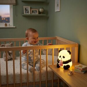 Veilleuse panda en silicone souple avec un biberon rose tenue dans les mains - Rituel Dodo.