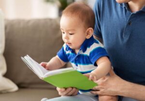 Père qui lit une histoire du soir à son bébé, lecture precoce rituel dodo